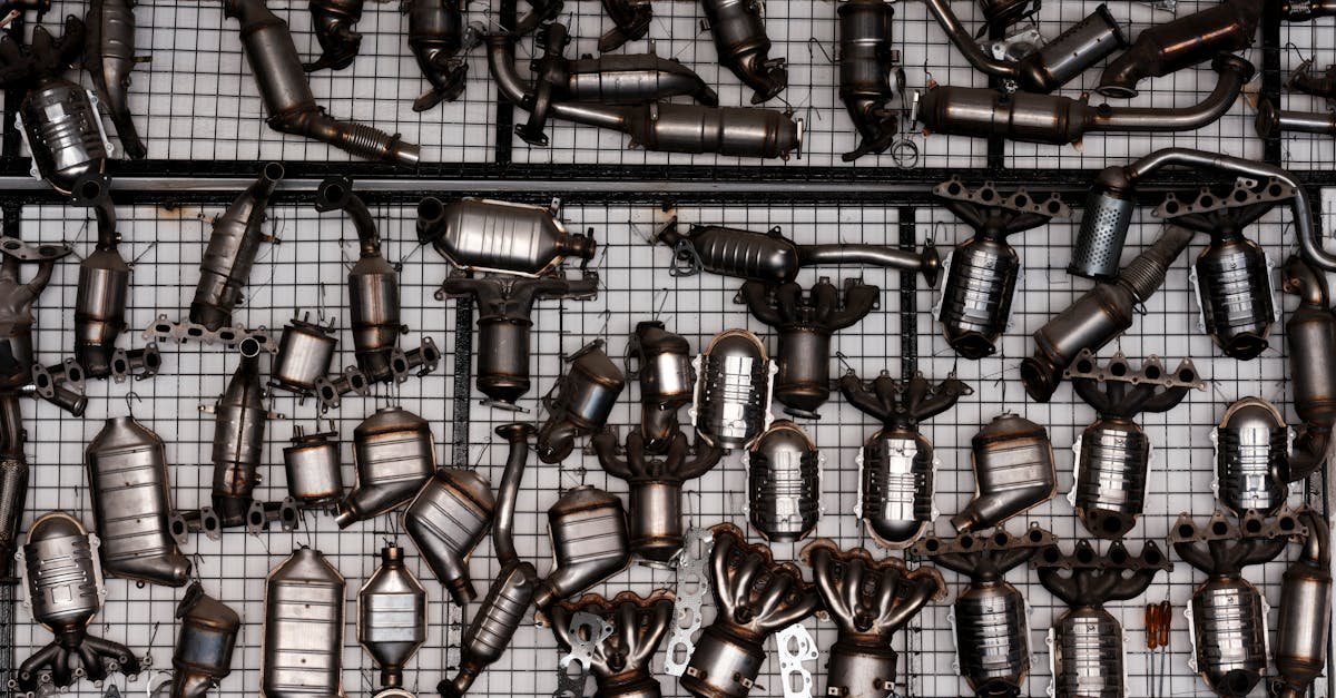 An array of automotive exhaust parts displayed on a grid wall in an industrial garage setting.